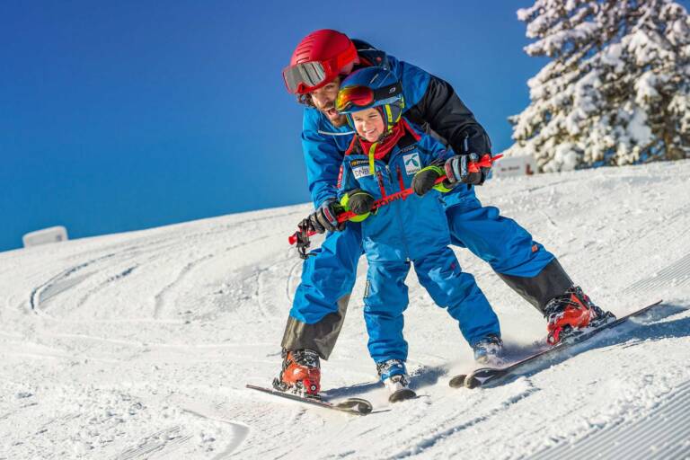 Skilehrer zeigt Jungen wie man Ski fährt